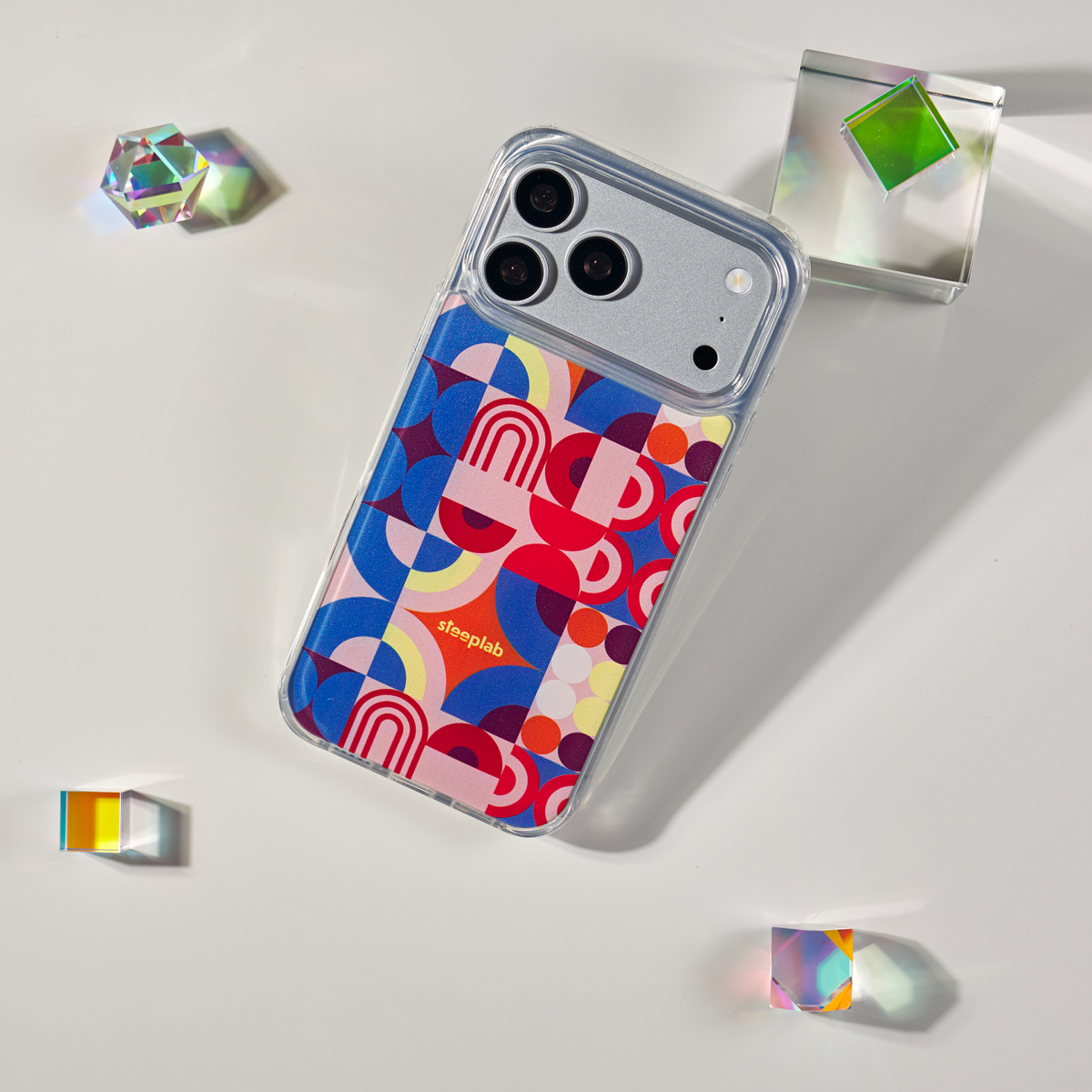 Freehand Case in Color Play for iPhone 18 Pro Max, multicolor geometric pattern, shown at an angle with crystal props.