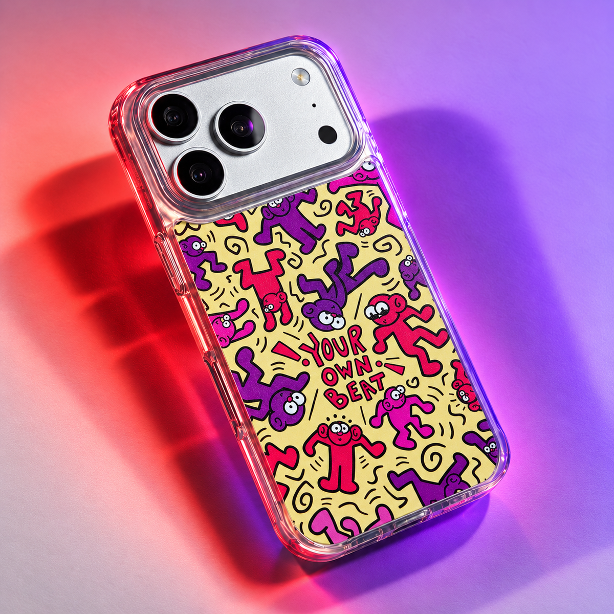Freehand Case in Doodle Dance for iPhone 18 Pro Max, yellow design with red and purple dancing characters, under colored gel studio lighting.
