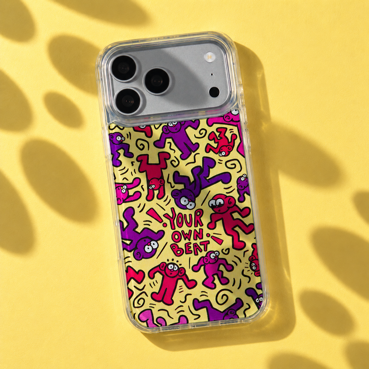 Freehand Case in Doodle Dance for iPhone 18 Pro Max, yellow design with red and purple dancing characters, with patterned studio light and shadows.