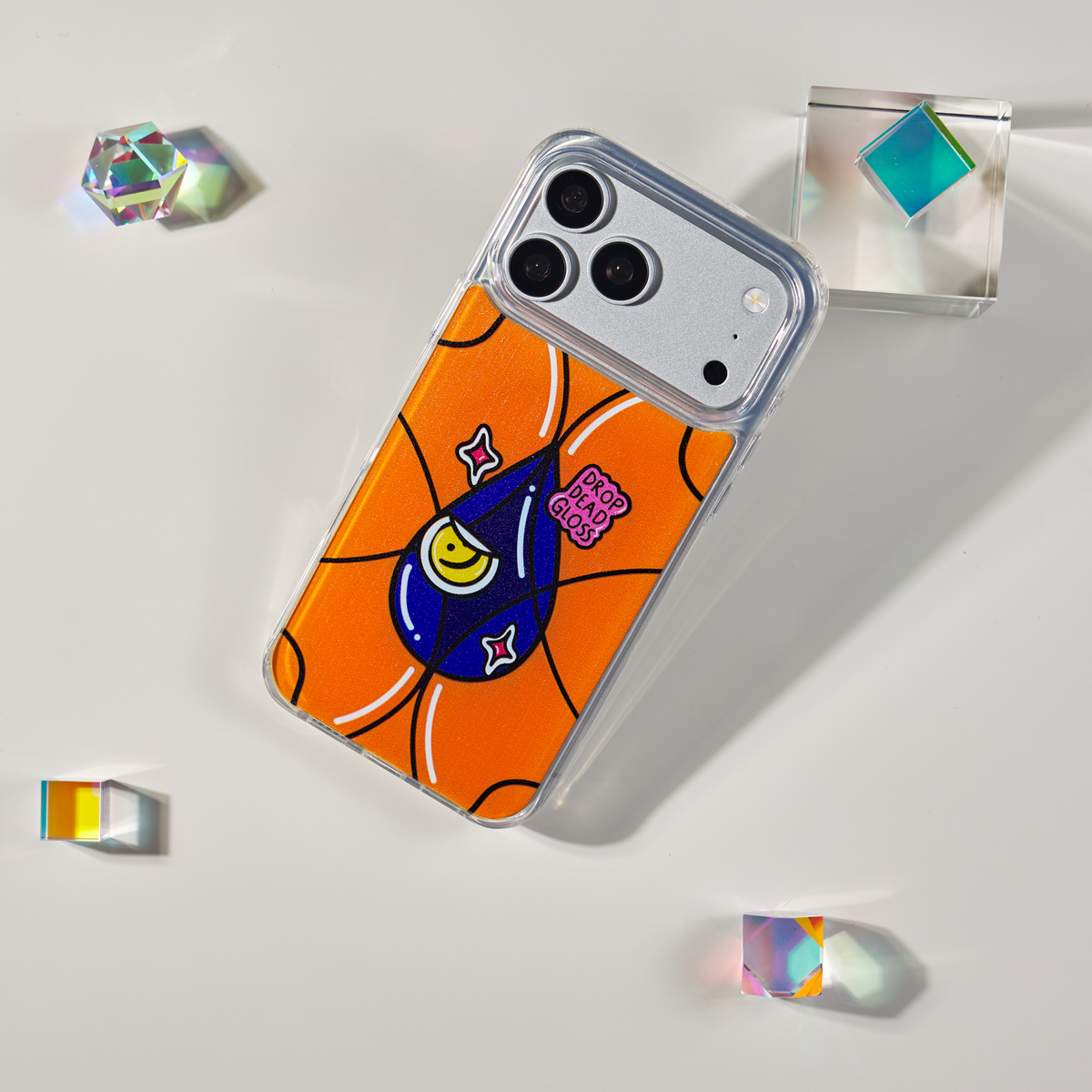 Freehand Case in Gloss Drop for iPhone 18 Pro Max, orange design with a blue illustrated drop, shown at an angle with crystal props.