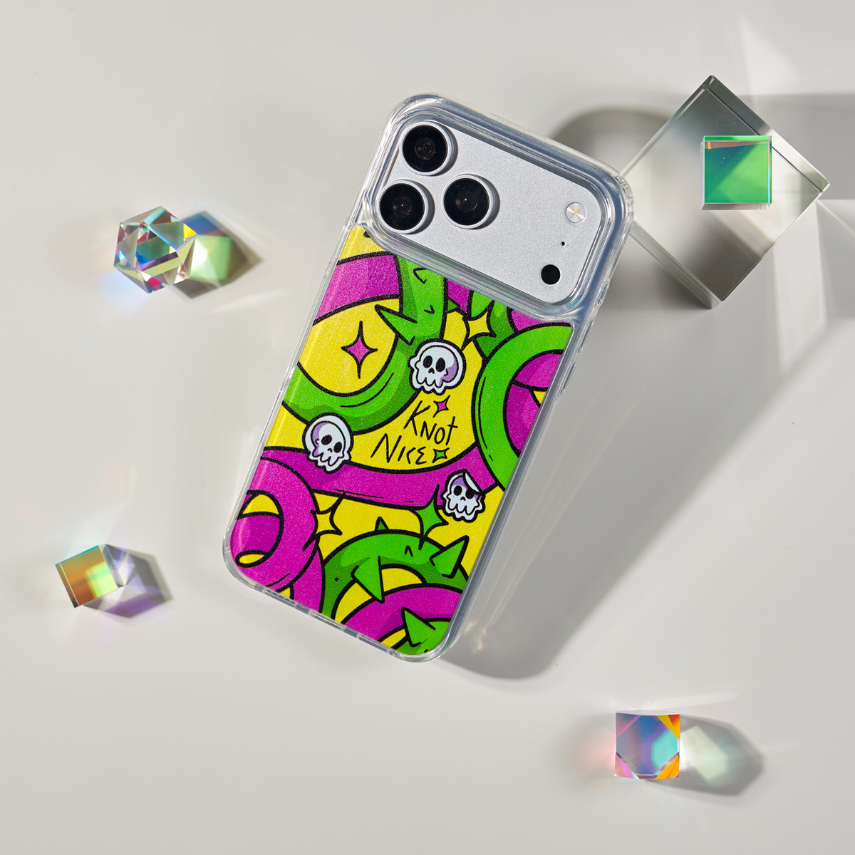 Freehand Case in Neon Knots for iPhone 18 Pro Max, bright yellow, pink and green ribbon design, shown at an angle with crystal props.