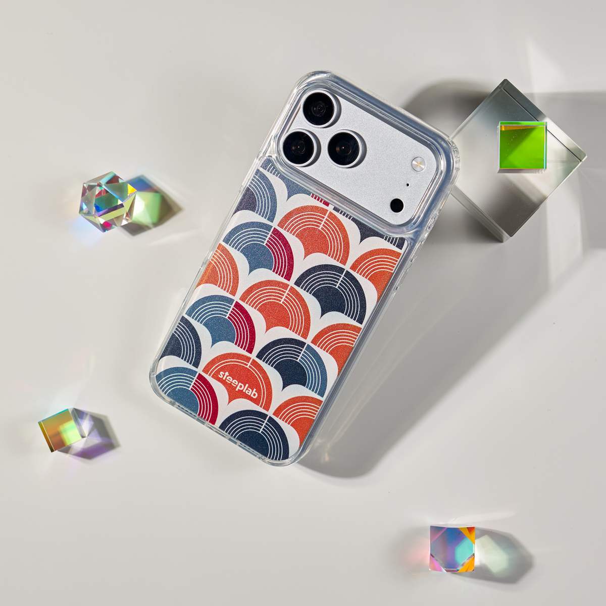 Freehand Case in Retro Ripple for iPhone 18 Pro Max, red and blue repeating arch pattern, shown at an angle with crystal props.