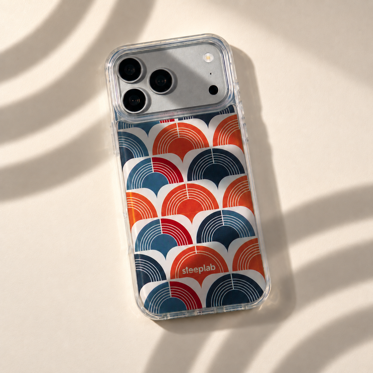 Freehand Case in Retro Ripple for iPhone 18 Pro Max, red and blue repeating arch pattern, with patterned studio light and shadows.