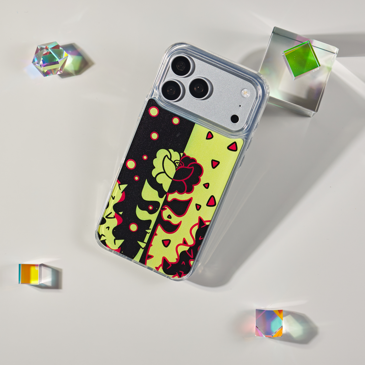 Freehand Case in Split Bloom for iPhone 18 Pro Max, black and chartreuse split floral design, shown at an angle with crystal props.