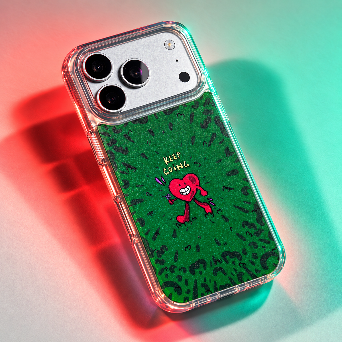 Freehand Case in Wild Heart for iPhone 18 Pro Max, green doodle design with a red walking heart, under colored gel studio lighting.