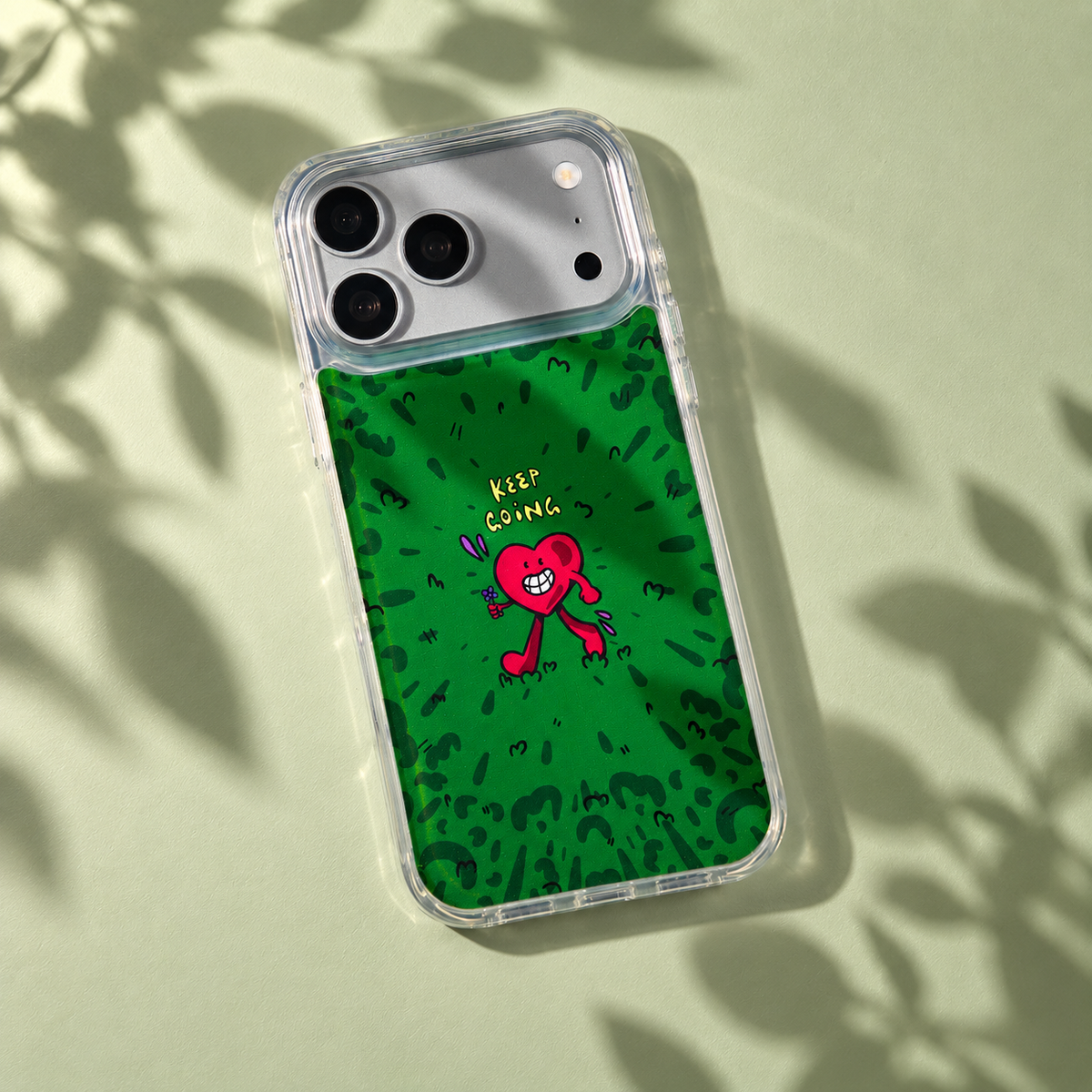 Freehand Case in Wild Heart for iPhone 18 Pro Max, green doodle design with a red walking heart, with patterned studio light and shadows.
